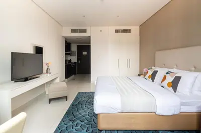 a bedroom with a large bed and a flat screen tv at Frank Porter - Damac Cour Jardin in Dubai