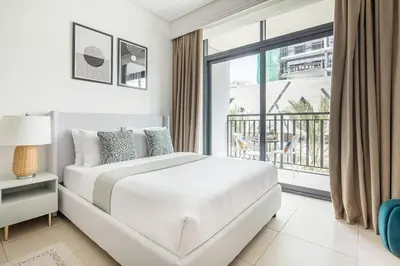 a white bedroom with a bed and a balcony at Frank Porter - Sunrise Legend in Dubai