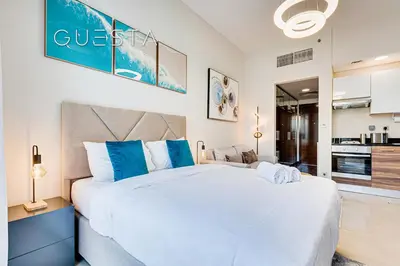 a bedroom with a large white bed with blue pillows at Sparkle Tower - Studio, Dubai Marina in Dubai