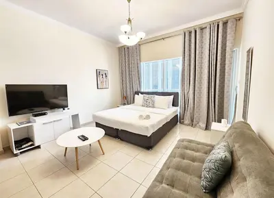 a living room with a bed and a couch and a tv at RH- Relaxing Studio, Downtown with private balcony, walk away from Burj Khalifa in Dubai