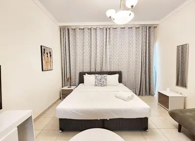 a bedroom with a white bed and a couch at RH- Relaxing Studio, Downtown with private balcony, walk away from Burj Khalifa in Dubai