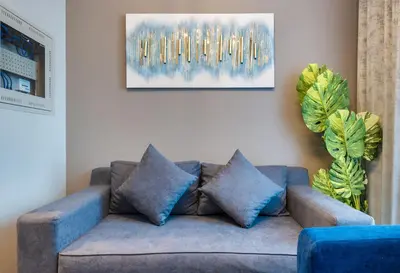 a living room with a blue couch and a painting at ALiving Luxury 1BR with Canal View I Near Burj Khalifa & Dubai Mall I Zada Tower, 2613 in Dubai