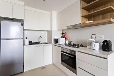 a kitchen with white cabinets and a stainless steel refrigerator at Silkhaus luxurious 1BDR in new tower with pool & gym in Dubai