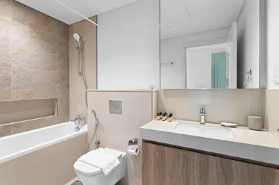 a bathroom with a sink and a toilet and a tub at Silkhaus luxurious 1BDR in new tower with pool & gym in Dubai