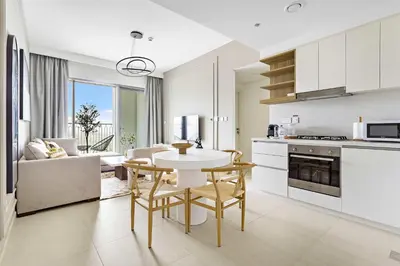 a kitchen and living room with a table and chairs at Silkhaus modern & chic 1BDR in new tower with pool & gym in Dubai