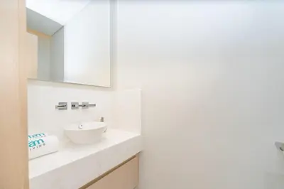 a white bathroom with a sink and a mirror at FAM Living - Palm Tower Attached to St Regis Palm Tower 1Bed - Palm Jumeirah Views in Dubai