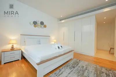 a white bedroom with a white bed and a table at Mira Holiday Homes - Fully furnished 1 bedroom in Bluewater in Dubai