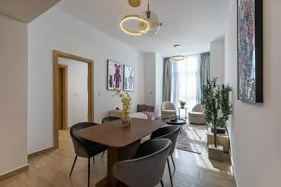 a dining room and living room with a table and chairs at Stunning 1 Bedroom Apartment - Regina Tower - JVC in Dubai