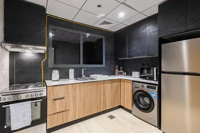 a kitchen with a refrigerator and a washer and dryer at Stunning 1 Bedroom Apartment - Regina Tower - JVC in Dubai