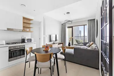 a kitchen and living room with a table and a couch at Silkhaus lavish 1BDR in new tower with pool & gym access in Dubai