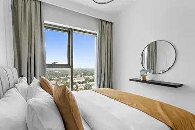 a bedroom with a bed and a large window at Silkhaus lavish 1BDR in new tower with pool & gym access in Dubai
