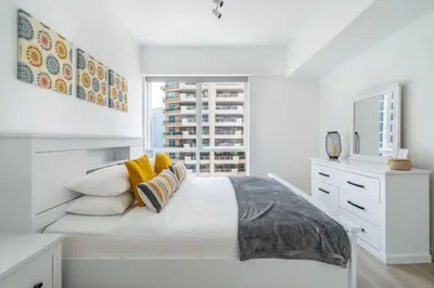 a white bedroom with a large bed with yellow pillows at GuestReady - Moment in time at Al Majara in Dubai