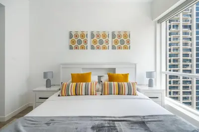 a white bedroom with a large bed with yellow pillows at GuestReady - Moment in time at Al Majara in Dubai