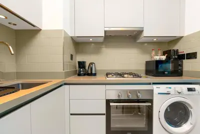 a white kitchen with a washer and a microwave at 10min from Burj Khalifa - Sobha Creek Vistas Réservé in Dubai
