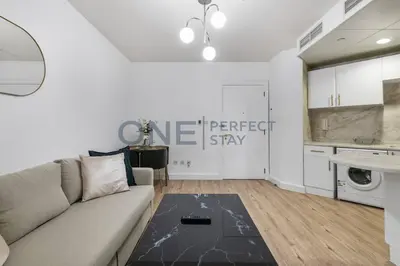 a living room with a couch and a kitchen at Stunning Lake View - Height Floor - Furnished 1BR in Dubai