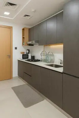 a kitchen with brown cabinets and a sink at Cozy Apartment in Jumeirah Village Circle, Dubai. in Dubai