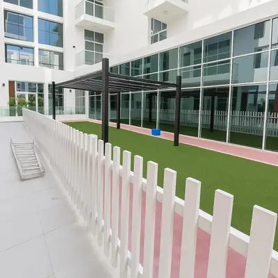 a white picket fence in front of a building at Cozy Apartment in Jumeirah Village Circle, Dubai. in Dubai