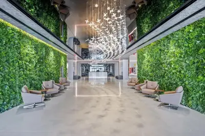 a lobby with a large green wall with chairs and plants at Appartement Dubai in Dubai