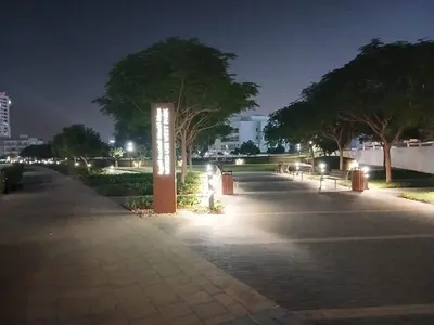 a walkway with lights in a park at night at Appartement Dubai in Dubai