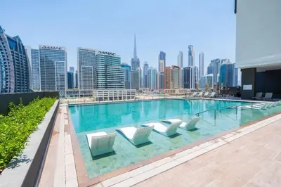 a swimming pool with chairs and a city skyline at Iconic !Luxurious 1 Bed Apartment! in Dubai