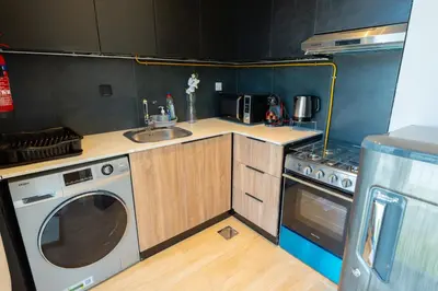 a small kitchen with a sink and a washing machine at Le Villa-Joie !Bright Studio Apartment! in Dubai