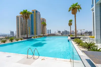a swimming pool on the roof of a building with palm trees at Le Villa-Joie !Bright Studio Apartment! in Dubai