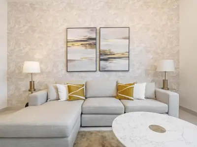 a living room with a couch and two paintings on the wall at Fantastic 1 BR in Park Point - Dubai Hills in Dubai