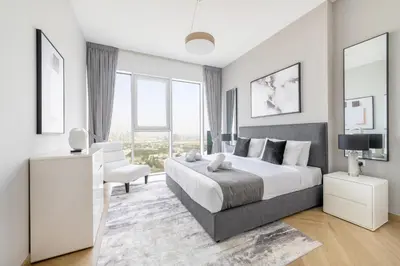 a white bedroom with a large bed and a chair at Ultra Luxury Wasl 1 Residences Zabeel Park in Dubai