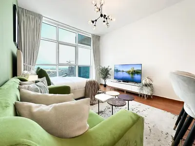 a living room with a green couch and a tv at Trophy - Urban Oasis Suite in Dubai
