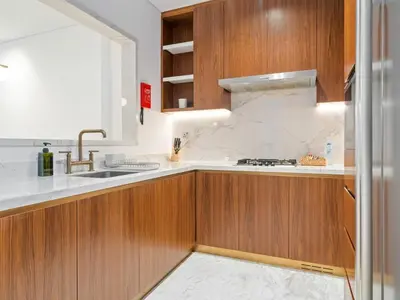 a kitchen with wooden cabinets and a sink at Elegant Apartment Amidst Vibrant Area With Balcony in Dubai