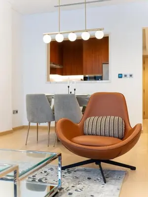 a brown chair in a living room with a table at Elegant Apartment Amidst Vibrant Area With Balcony in Dubai