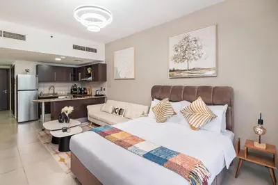 a bedroom with a large bed and a kitchen at Furnished studio in Arch Tower, JLT near metro in Dubai