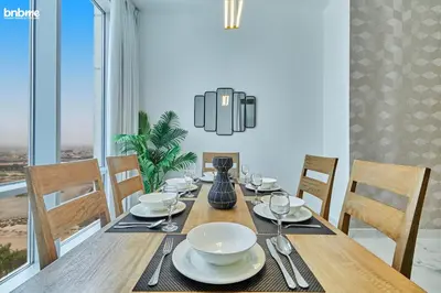 a dining room with a wooden table with chairs and a dining room at bnbme - Luxury 2BR Business Bay Apt w Canal Views Pool Gym Free Parking Downtown in Dubai