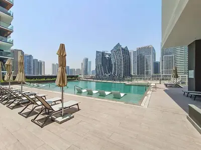 a swimming pool with chairs and umbrellas on a building at Stylish studio next to canal in Dubai