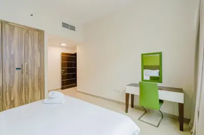 a bedroom with a bed and a desk with a green chair at RH- Spacious, Stylish, 01BR near Mall of Emirates in Dubai