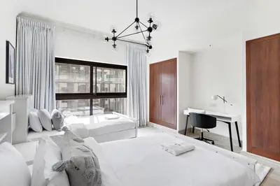 a white living room with a bed and a desk at StoneTree - Fairmont South 2 BR - Near Beach in Dubai