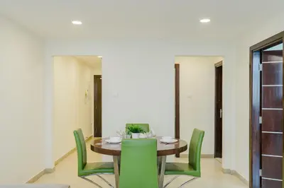 a dining room with a table and green chairs at RH-Prime Location , Spacious 1 Bedroom near Mall of the Emirates in Dubai