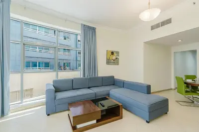 a living room with a blue couch and a table at RH-Prime Location , Spacious 1 Bedroom near Mall of the Emirates in Dubai