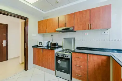 a kitchen with wooden cabinets and a stove top oven at RH- Huge, Comfortable 01 BR Apartment in Barsha1 in Dubai