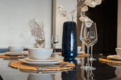 a table with glasses and plates and a blue vase at GuestReady - A Glimpse of Burj Al Arab in Dubai
