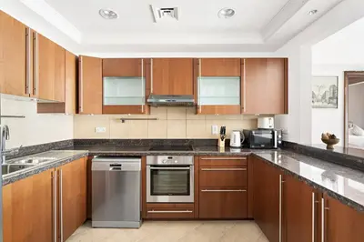 a kitchen with wooden cabinets and stainless steel appliances at StoneTree - Golden Mile 5 2BR - Near Nakhil Mall in Dubai