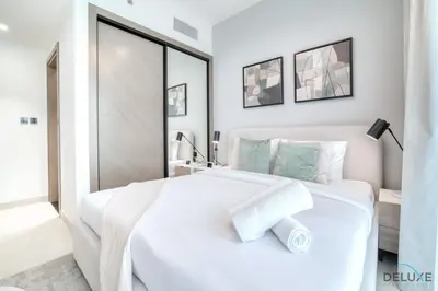 a white bedroom with a large white bed with towels on it at Polished 1BR at Binghatti Creek Al Jadaf by Deluxe Holiday Homes in Dubai
