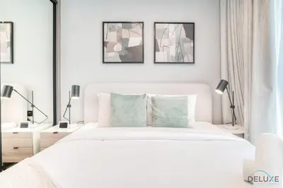 a white bedroom with a white bed and three pictures on the wall at Polished 1BR at Binghatti Creek Al Jadaf by Deluxe Holiday Homes in Dubai