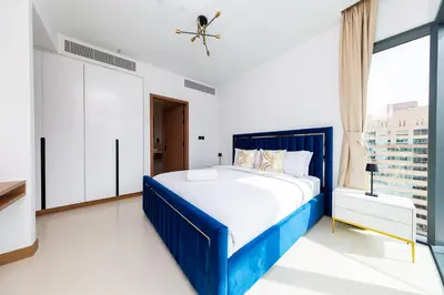 a blue bed in a white room with a window at BRAND-NEW 1 Bedroom with full Marina View in Dubai