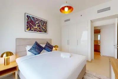 a white bedroom with a large bed and a desk at Vacationer l 1 Bedroom on Low Floor l Close to Burj Khalifa l Pool Access & Free Wi-Fi in Dubai