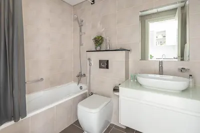 a bathroom with a toilet and a tub and a sink at Frank Porter - Carson A in Dubai