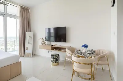 a white room with a dining table and a tv at Frank Porter - Carson A in Dubai