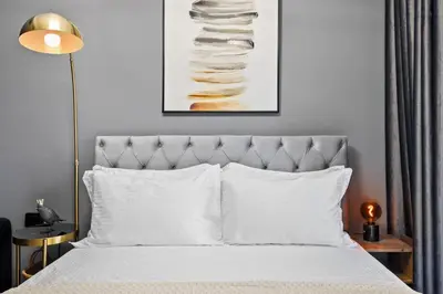 a bedroom with a bed with white pillows and a painting at Luxury studio at JLT near metro in Dubai