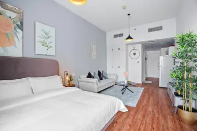 a bedroom with a bed and a living room at Stylish studio at Sports City in Dubai