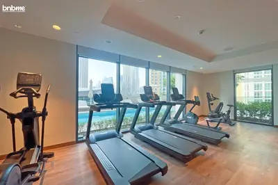 a gym with treadmills and ellipticals in a room with windows at bnbme - Luxury 1BR Apt w Burj Khalifa Views Pool Gym & Prime Location Near Dubai Mall in Dubai